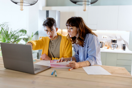 mother and teen looking at documents and laptop