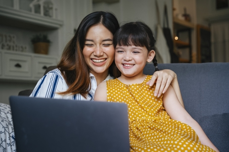 mother and daughter smiling and looking at a laptop